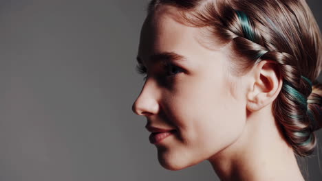 close-up profile of a woman with a braided hairstyle and colorful highlights
