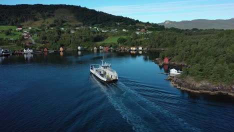 electric ferry ytteroyningen soon to arrive at utbjoa ferry pier norway - aerial crossing behind vessel with lush green landscape background