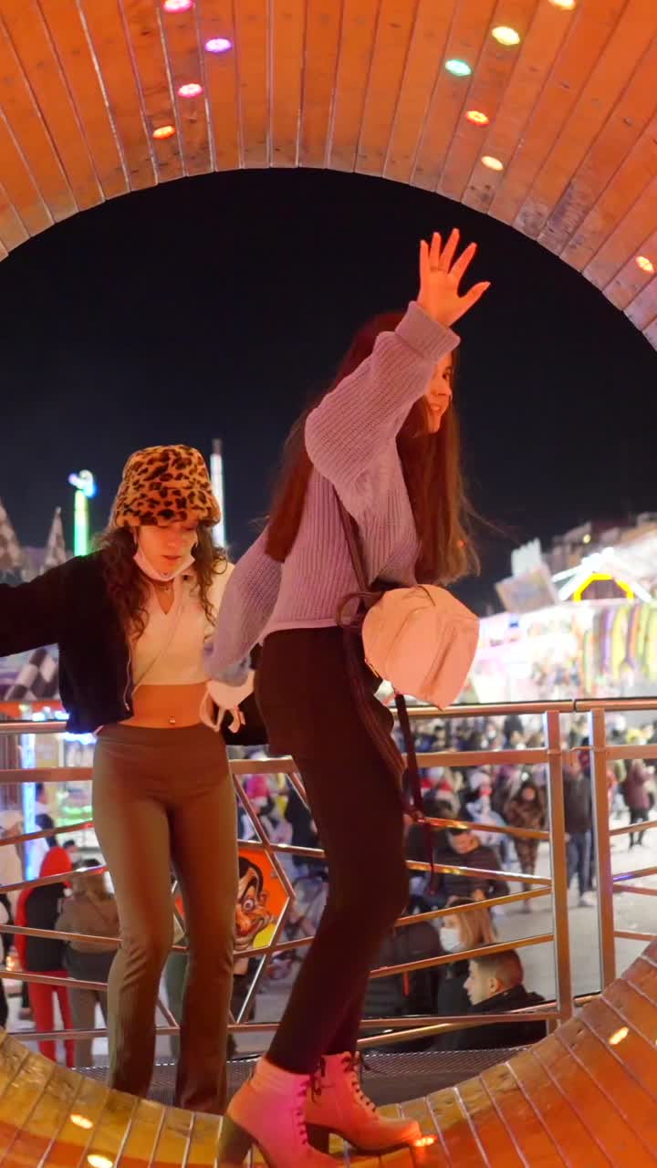 Young Women Enjoying a Fun Night at an Amusement Park with Changing Lights