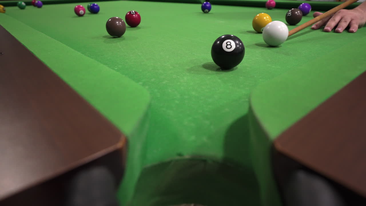 Billiard player preparing to shoot the black eight-ball with white ball towards the corner