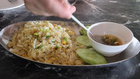 persona comiendo arroz frito con pepino y salsa