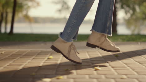 Playful-girl-legs-walking-sunny-slabbed-road-park-leaving-shadow-behind-closeup.