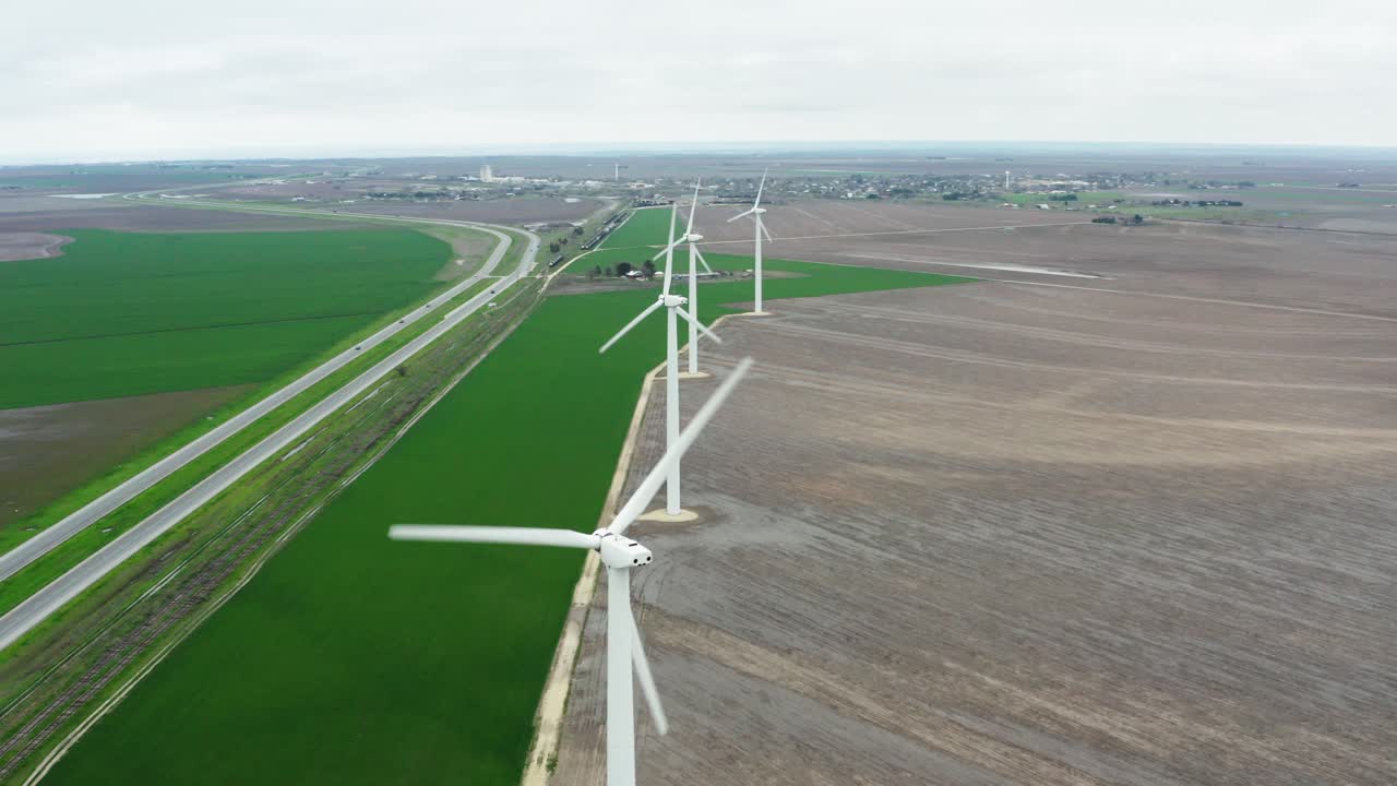 Row of green power windmills in orbiting drone view