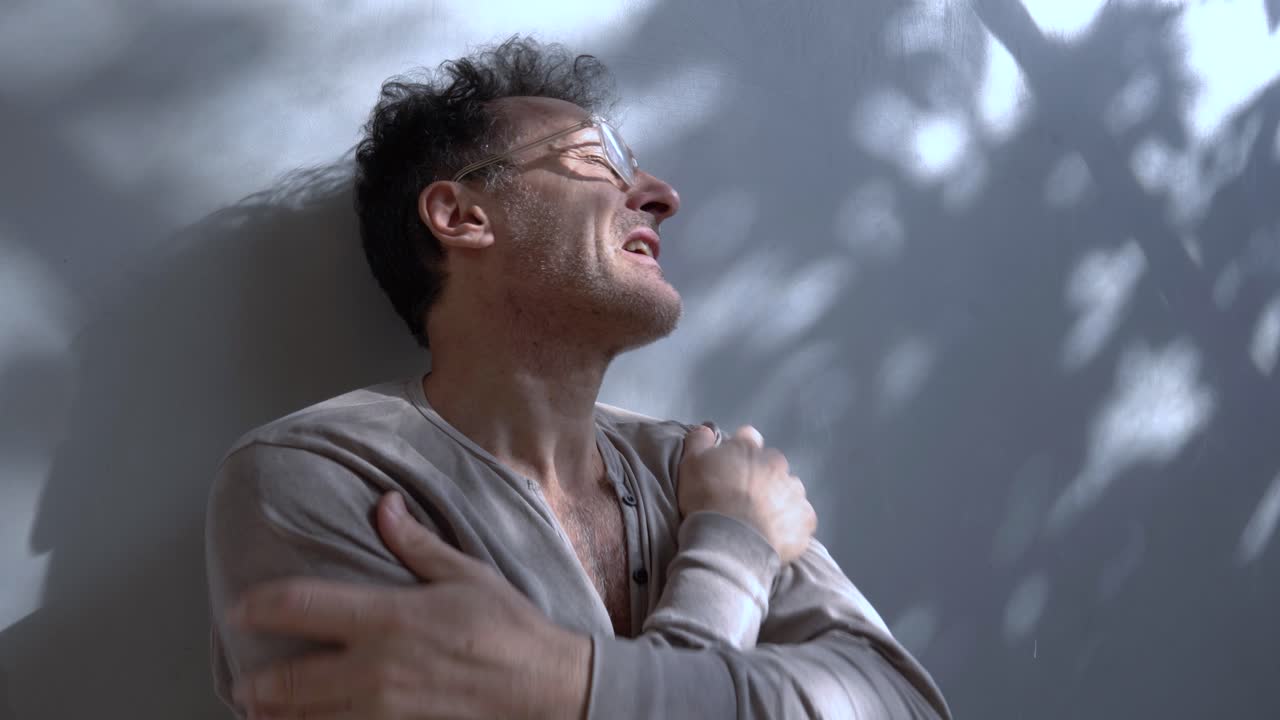 un hombre jurando gafas con una expresión preocupada se mueve ansiosamente en la pared