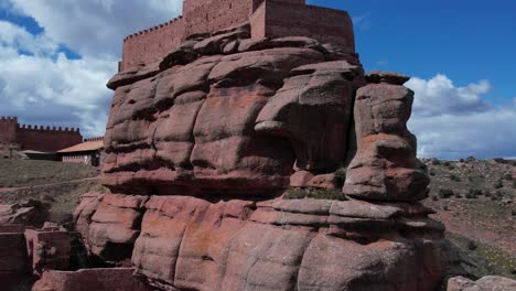 Aerial-drone-view-of-the-Castle-of-Peracense,-in-Teruel-,-built-in-the-X-century-with-red-sanstone-in-the-top-of-a-hill-with-a-nice-changing-sky