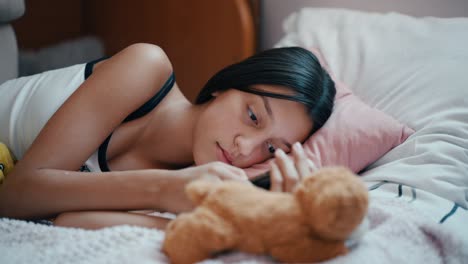 십대 소녀가 침대에 게으르게 누워서 드폰으로 소셜 미디어를 스크롤하고 있습니다.