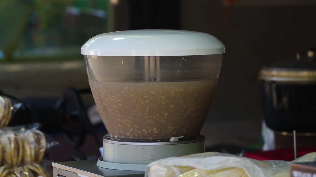 Close-up shot of the process of making Sikhye, a sweet Korean rice beverage, showing the liquid and floating rice grains inside a blending or brewing container