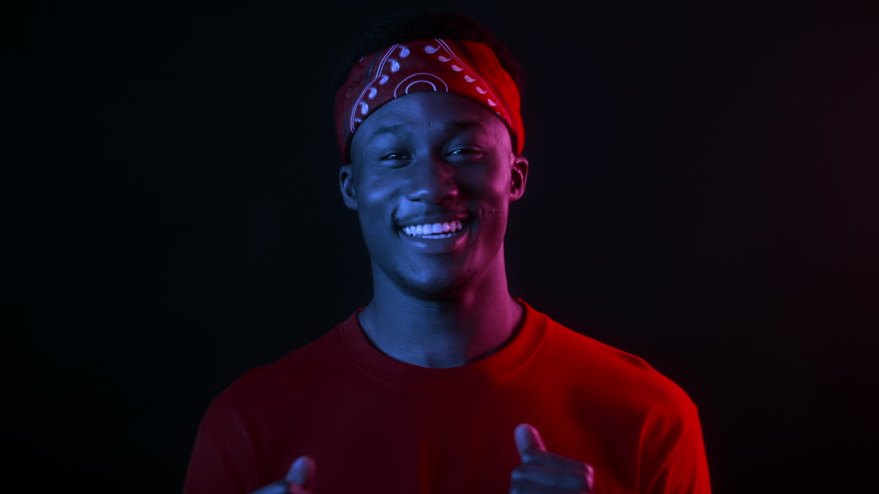 портрет улыбающегося человека в красной бандане и неоновом свете