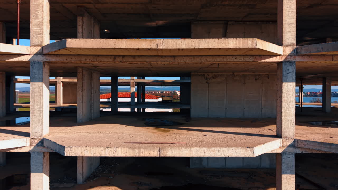 Empty floors of the multi-storied building under construction. Rising to the top of the building revealing view on the green fields and cityscape