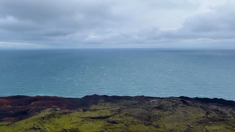 vast ocean view with rugged volcanic coast under cloudy sky at vestmannaeyjar, iceland