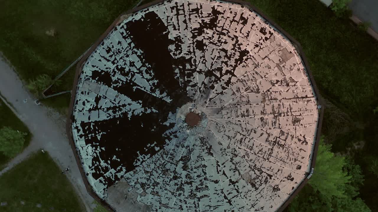 aéreo: movimiento de cámara giratorio lento sobre una torre de tanque de agua durante la puesta de sol