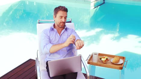 handsome man using laptop on deck chair