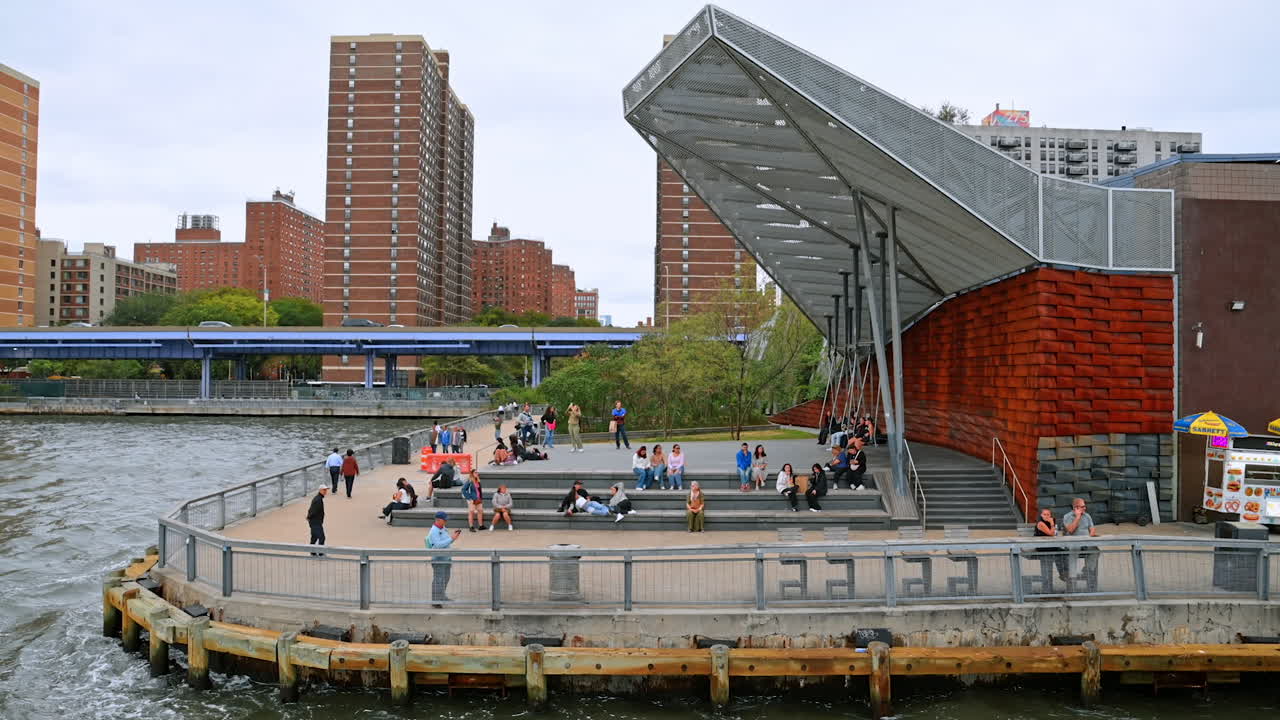 People spend time at the pier of New York, USA. View on the metropolis waterfront from the riverscape