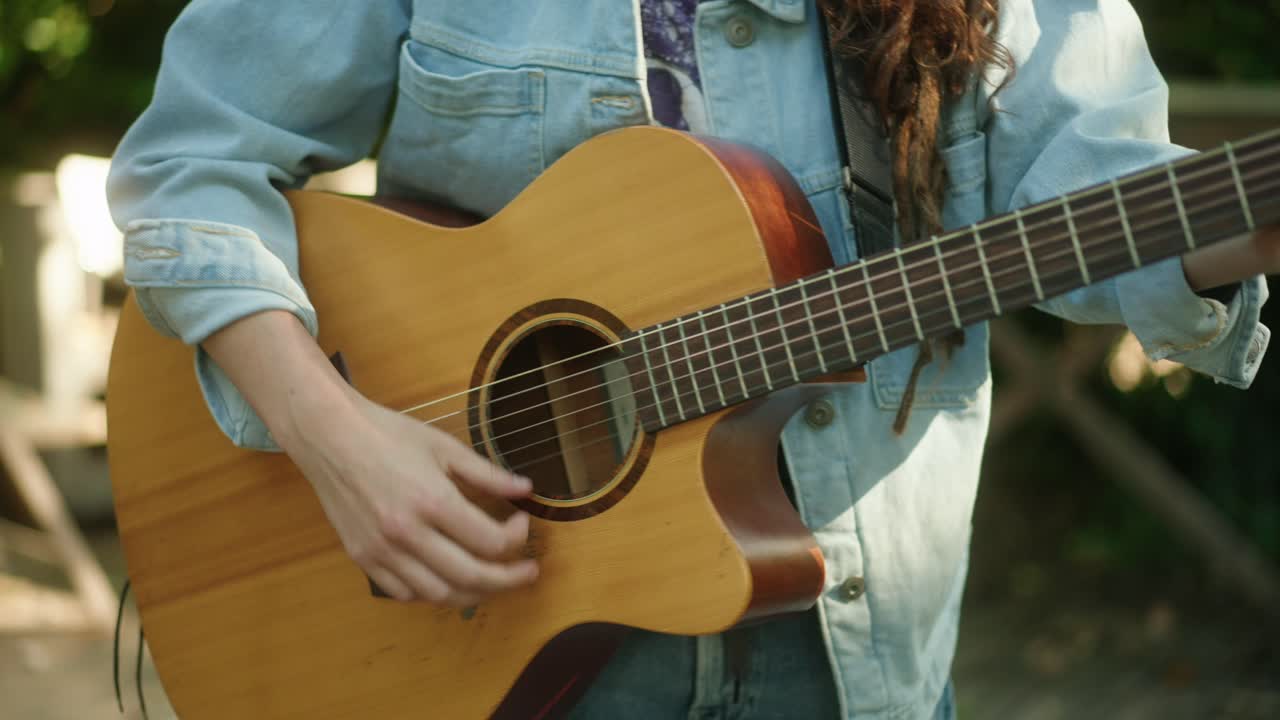 primer plano de guitarra acústica artista femenina jugando afuera