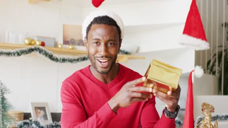 happy african american man wearing santa claus hat and having video call