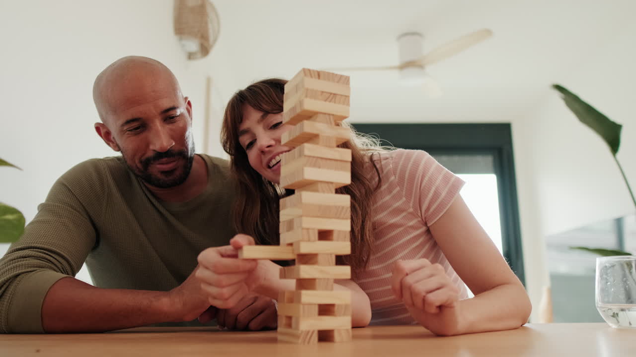 Mixed-race Couple Having Fun Playing Jenga at Home