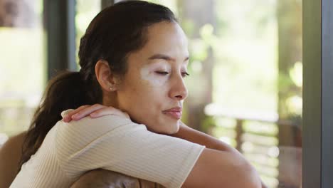 profile of relaxed biracial woman sitting on sofa at window and looking outside