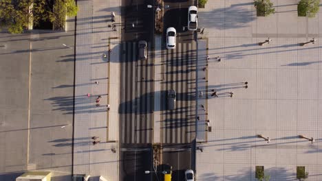 vista aérea de drones sobre vehículos de tráfico y una multitud de peatones cruzando la calle a la luz del atardecer