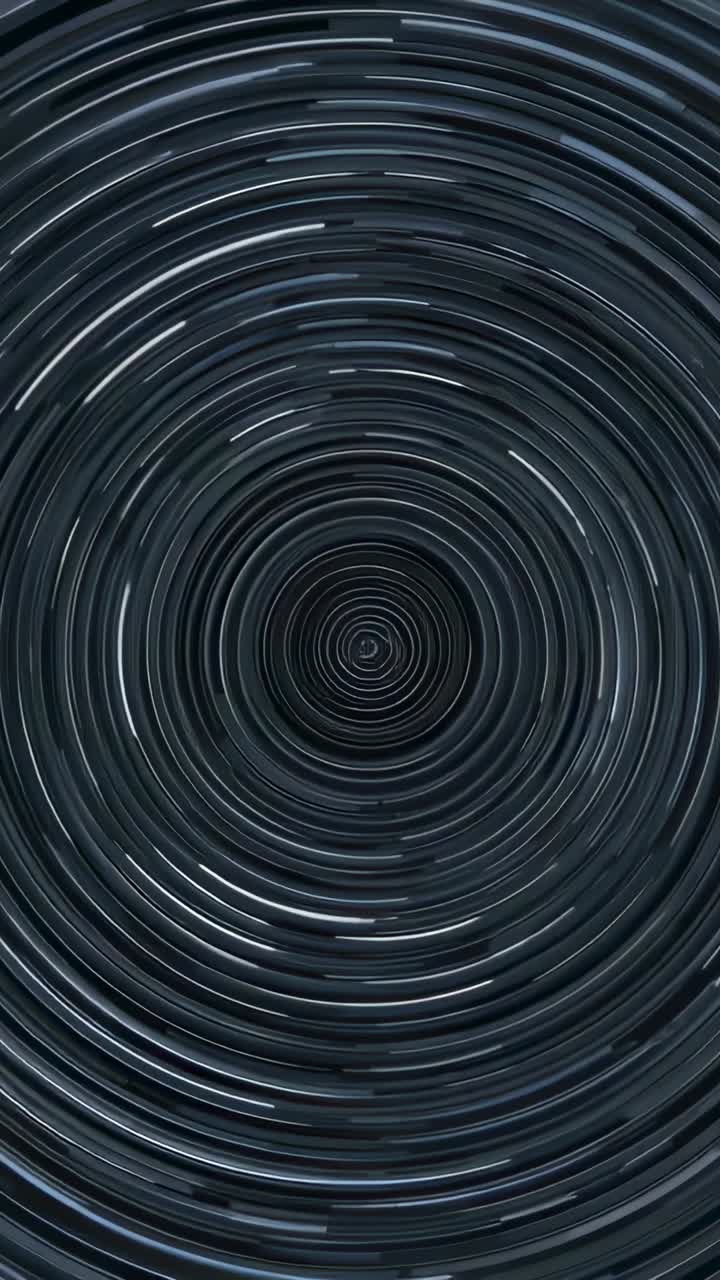 Vertical video: Starting metal spiral turning in tall frame rings sending lit glints making vortex