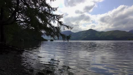 Gentle-waves-lap-the-stone-beach-of-Derwent-Water-in-the-Lake-District,-Cumbria,-England