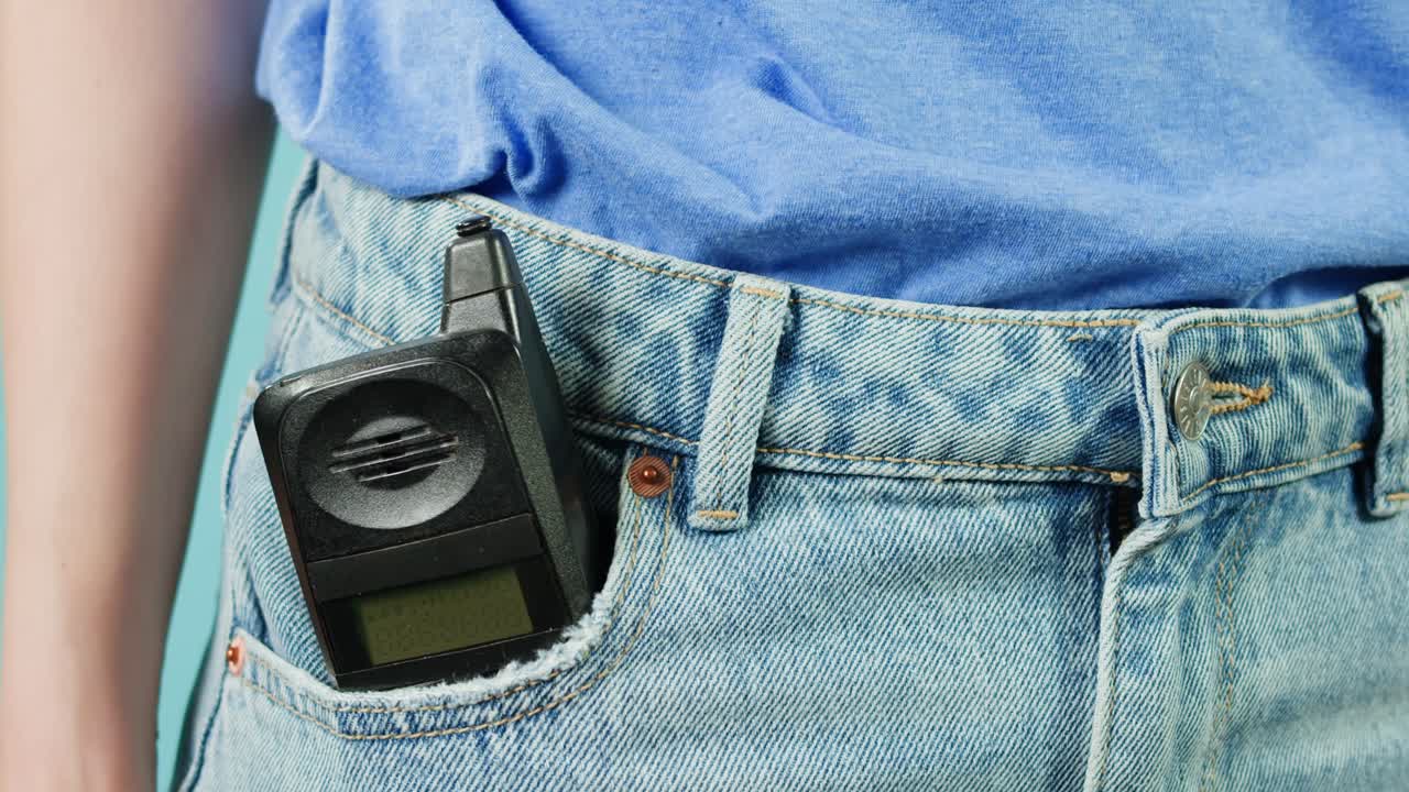 mujer con un viejo teléfono flip en el bolsillo de los vaqueros