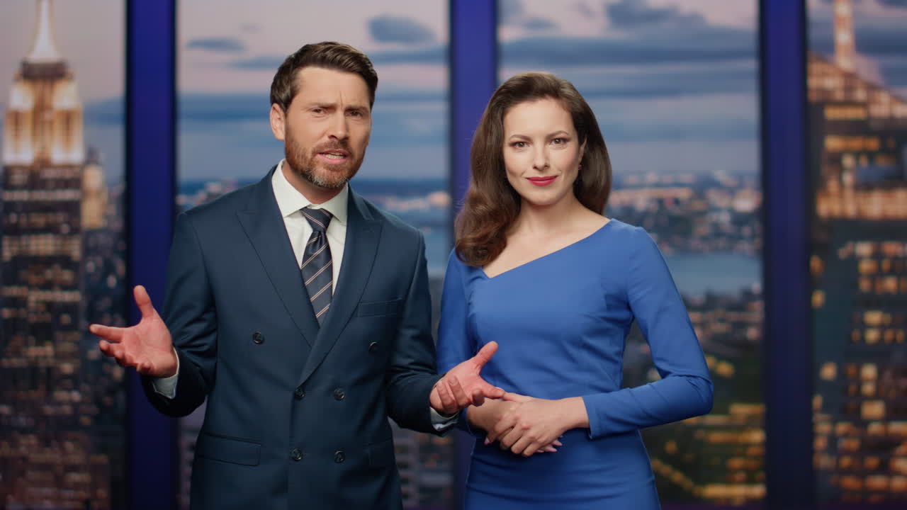 una pareja de anfitriones reportando noticias de última hora en el estudio del canal multimedia de cerca.