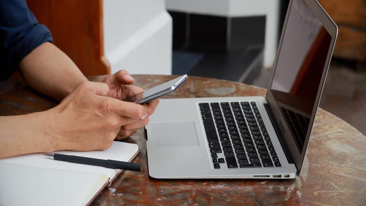 uomo che usa laptop e telefono cellulare in un caffè all'aperto 4k