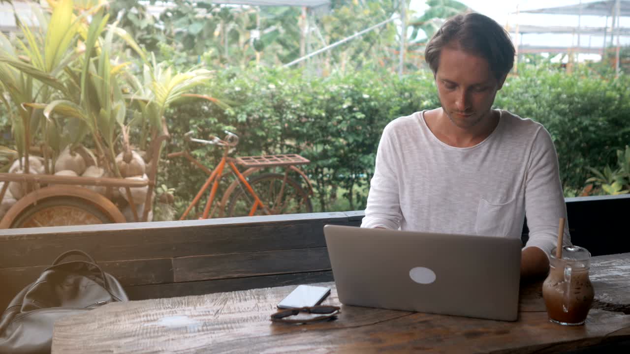 young man freelancer working on a laptop in outdoor cafe