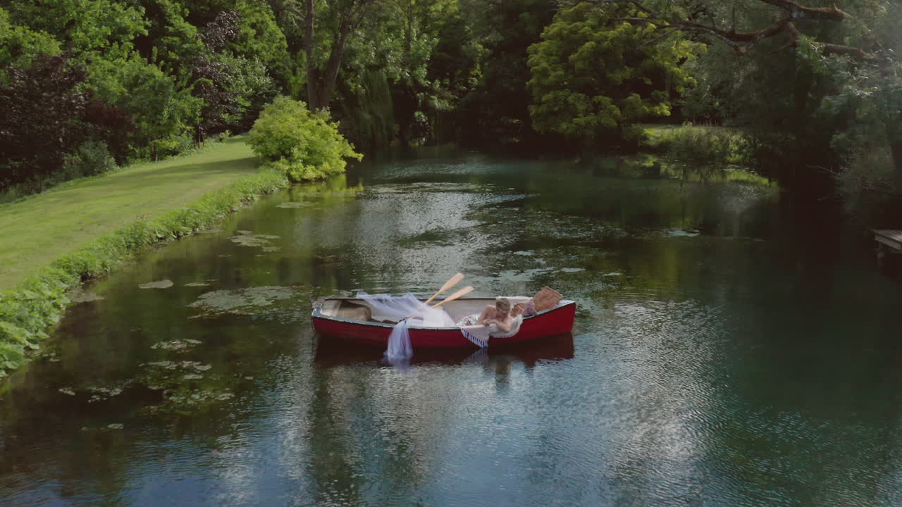 A Beautiful Sexy Woman Relaxing On The Rowing Boat With Green Trees At The Background - Drone Shot