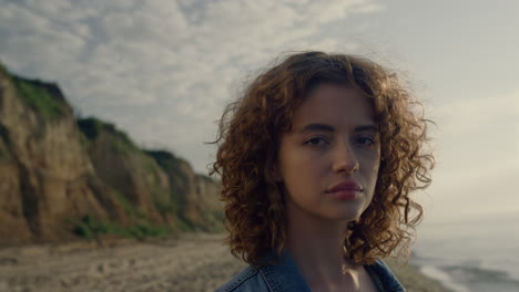 Glamour-girl-looking-at-camera-on-sea-beach.-Sensual-woman-touching-curly-hair