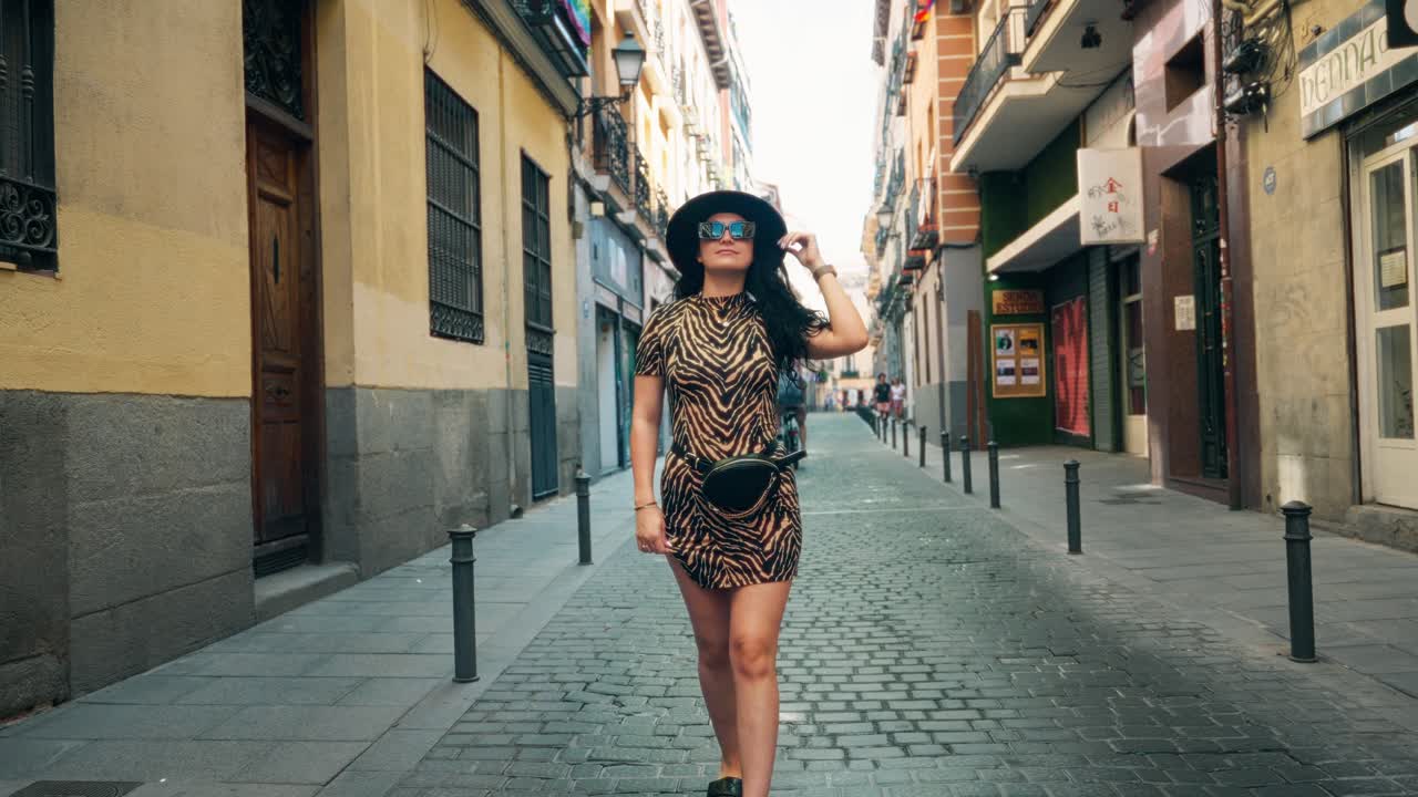 chica caminando por las calles de españa, edificios de estilo antiguo, vestido de cheta, con sombrero negro