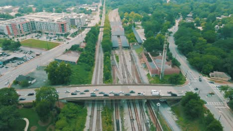 drone footage of a train station and car traffic going over a bridge