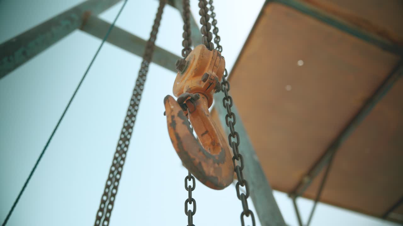 Rusty crane hook with chain on a construction site
