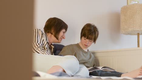 mother kissing her daughter while she is reading a book