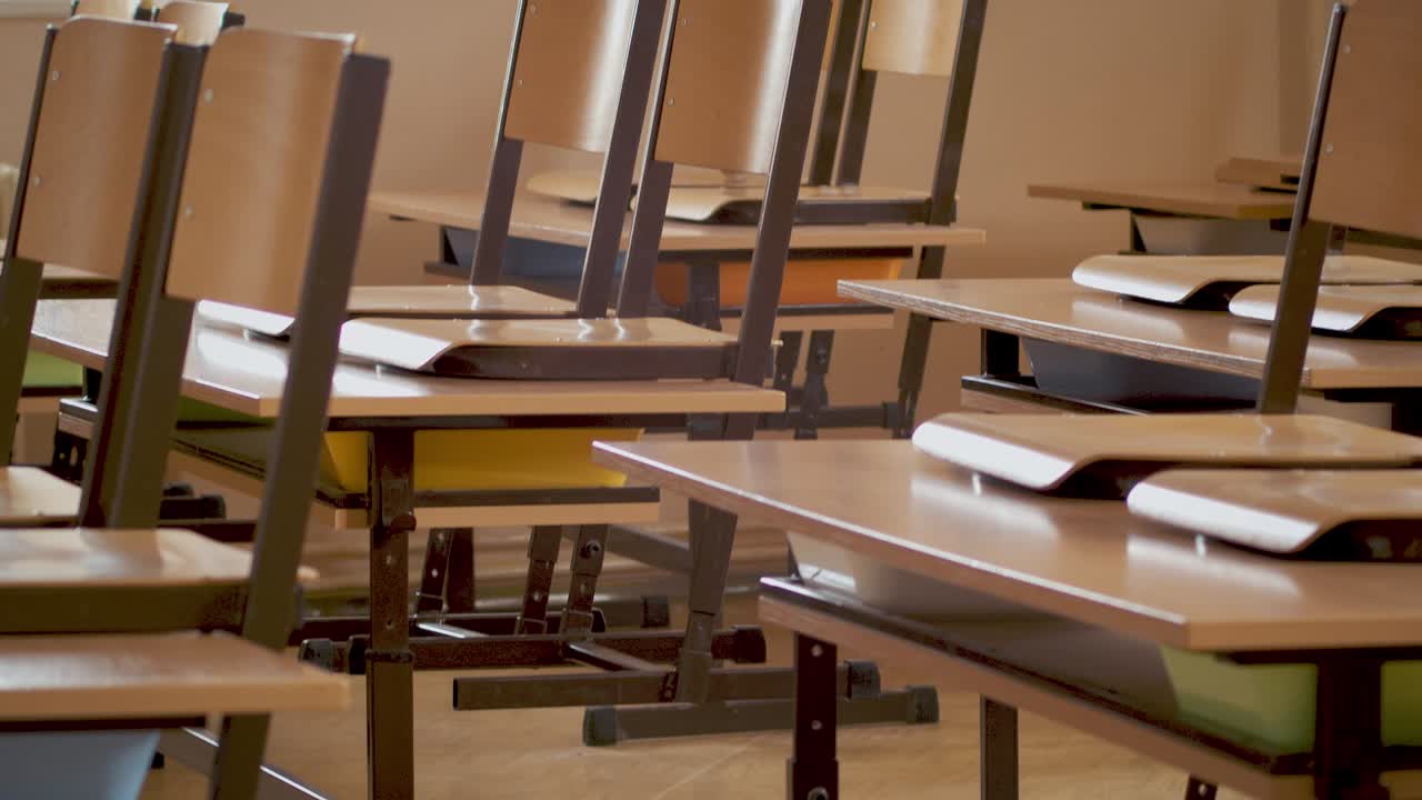 Shot of an abandoned row of tables and chairs in an empty classroom during a pandemic