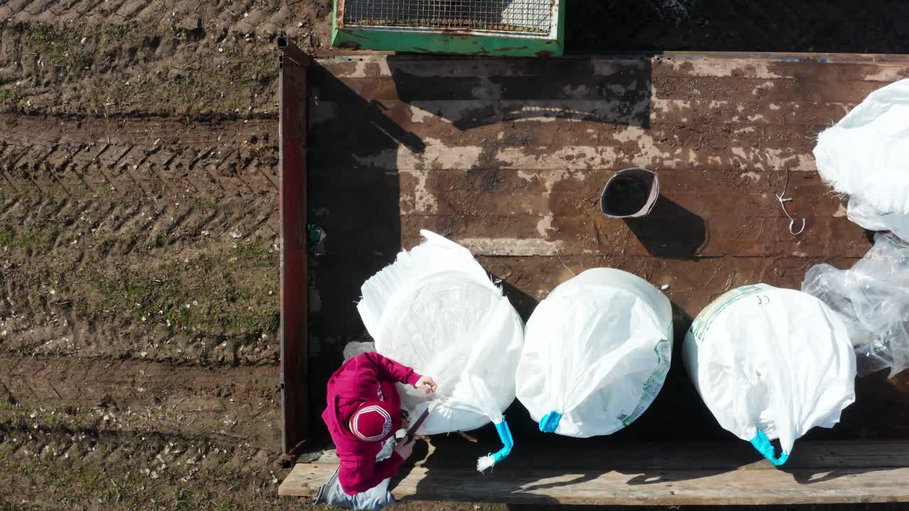 High angle view of farmer open big bag with mineral fertilizer in trailer