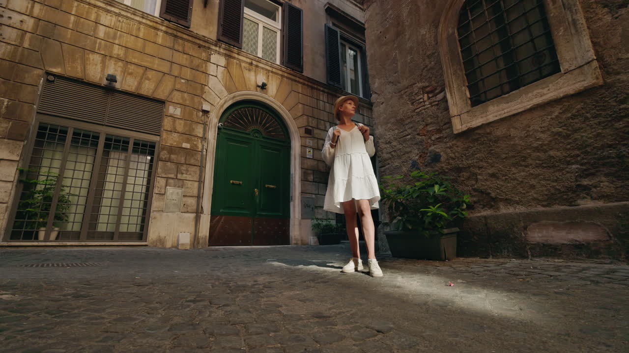Woman in white dress standing on cobblestone street in European town
