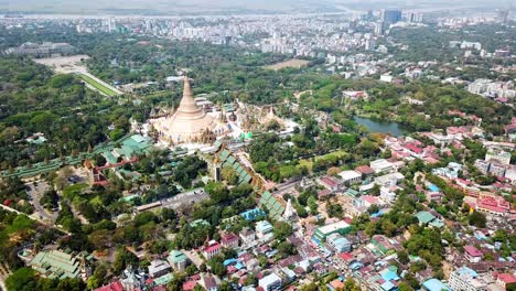 un dron captura la pagoda shwedagon, una magnífica estupa dorada, rodeada de exuberante vegetación y desarrollo urbano en rangún, myanmar, que muestra la mezcla de vida religiosa y moderna de la ciudad.