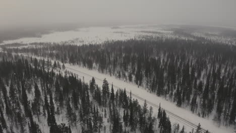 Toma-Aérea-De-Una-Carretera-En-Un-Bosque-De-Laponia-En-Invierno-Con-Fuertes-Nevadas