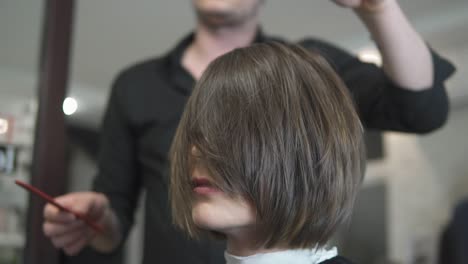 Peluquero-Profesional-Usando-Cepillo-Después-Del-Corte-De-Pelo.-Mujer-Joven-Vistiéndose-El-Pelo-En-Una-Peluquería.-Estilista-Con-Un