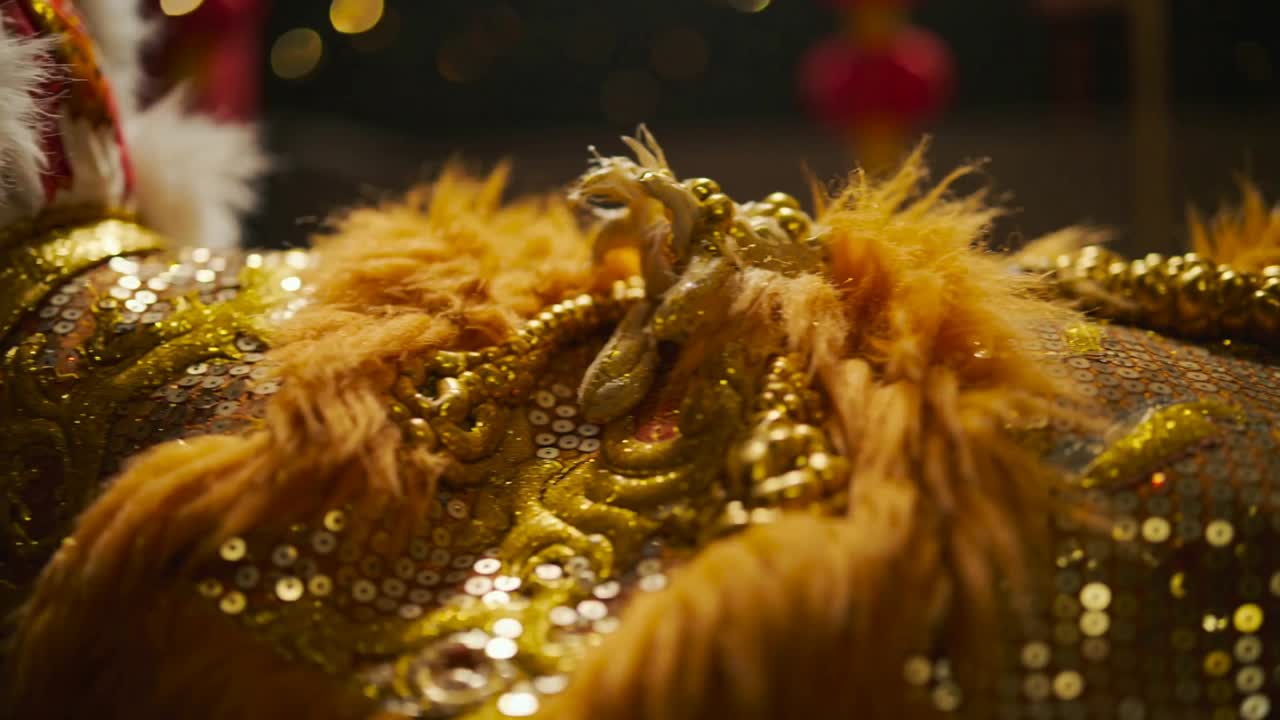 Câmera panorâmica revelando uma fantasia de lantejoulas em tons de laranja e dourado com pele sintética no palco, descobrindo um painel ornamentado
