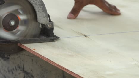 trabajador de la construcción cortando tablas de madera con sierra eléctrica circular al aire libre