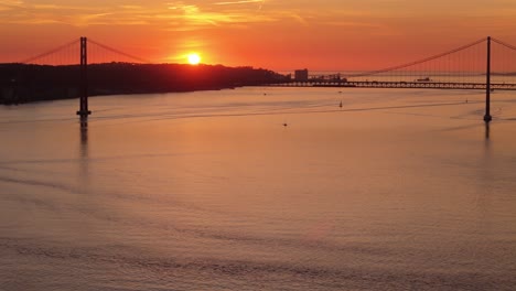 Aerial-establishing-of-suspension-bridge-silhouette-with-red-orange-haze-sky-at-sunset