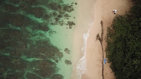 Vista-Aérea-Moviéndose-Por-Encima-De-Las-Olas-Rompiendo-En-Una-Playa-De-Arena-Tropical