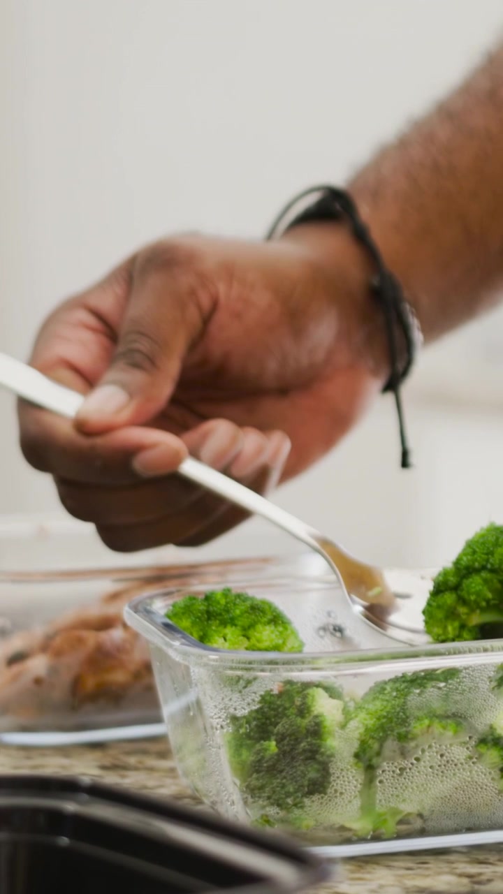 Vertical video: Hovering over rice on counter hands in yellow top serving broccoli next to rice