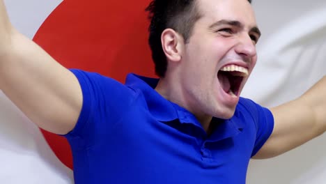 japanese young man celebrating while holding the japanese flag in slow motion