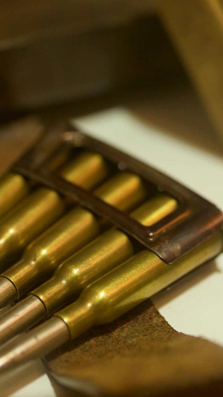 Detailed macro view of historical rifle cartridges in a museum, warm lighting, slow camera pan