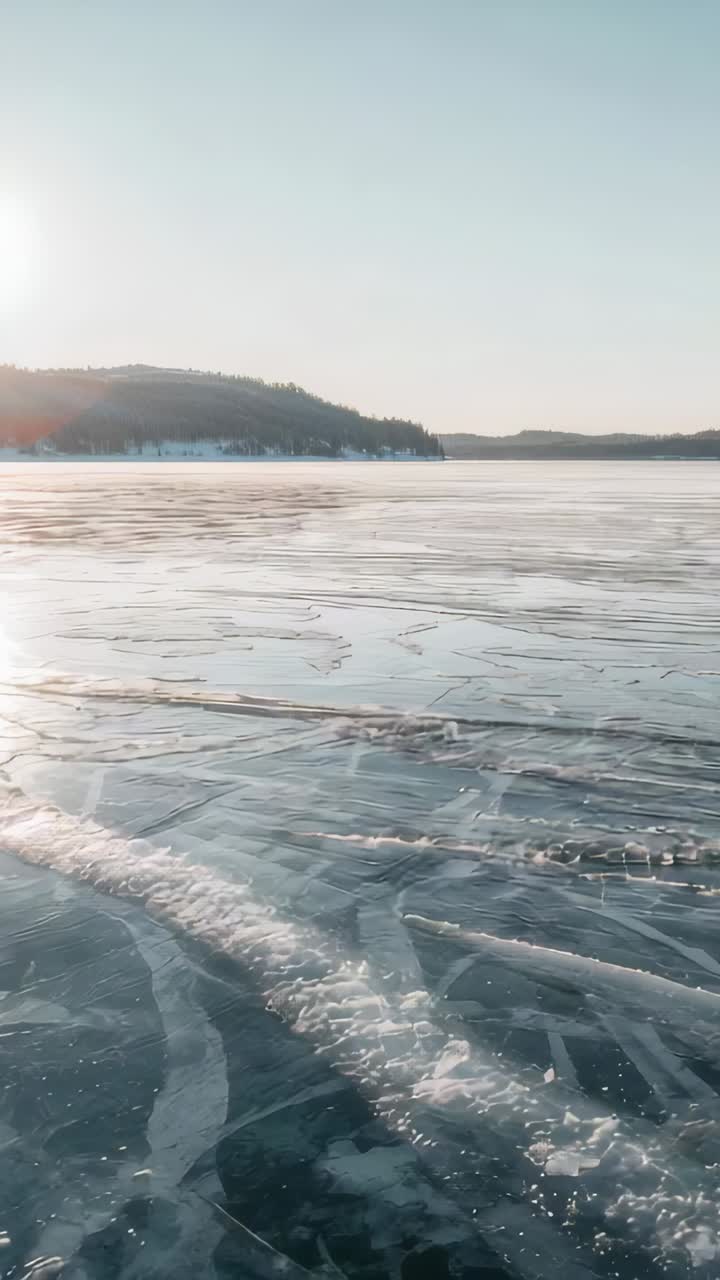 Vertical video: Moving camera revealing frozen lake with radial cracks at shore to show texture