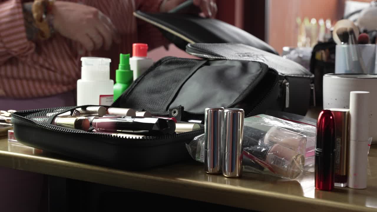 Still shot of table full of makeup, brushes and other accessories