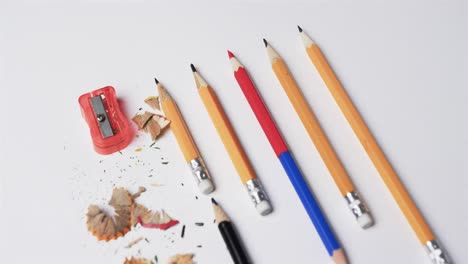 close up of pencils and pencil sharpener on white background, in slow motion